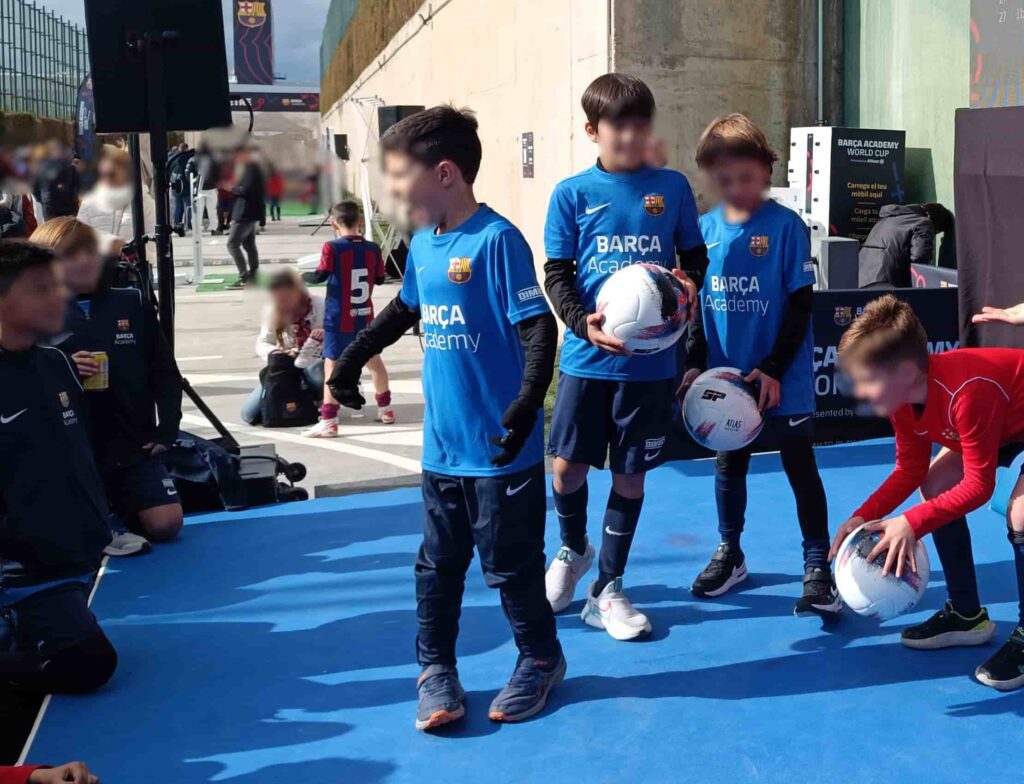 Niños participando en un taller interactivo de fútbol freestyle impartido por TOP TEAM FREESTYLERS en la Fanzone de FC Barcelona en la Ciudad Deportiva